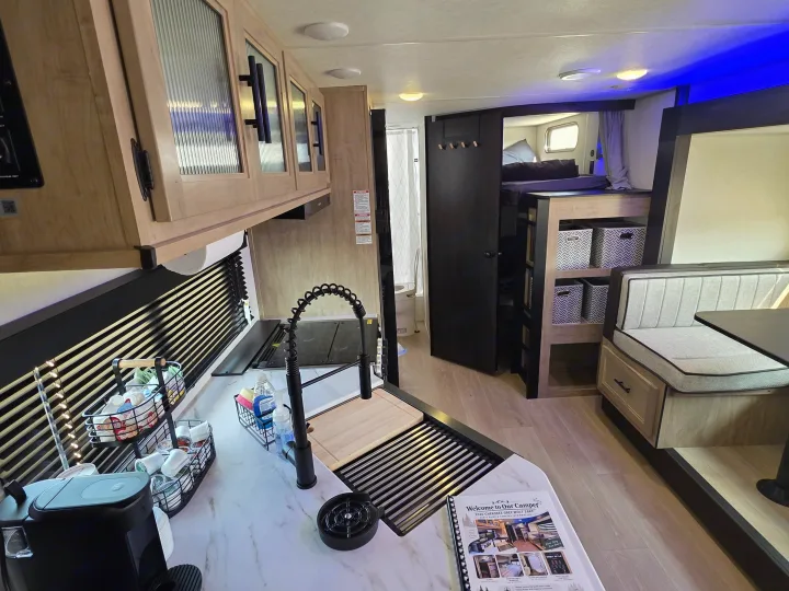 Inside a well-equipped RV rental: kitchen with coffee station, dining booth, and bunk beds. Ready for your next adventure.. Forest River Cherokee Grey Wolf 26KF 2026