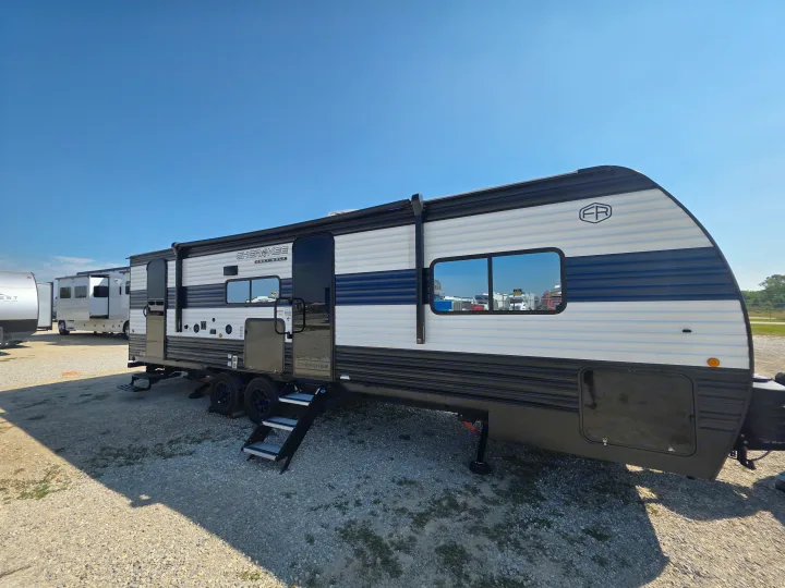 A modern Cherokee Grey Wolf travel trailer, white with blue stripes, ready for your RV rental journey on a sunny day.. Forest River Cherokee Grey Wolf 26KF 2026