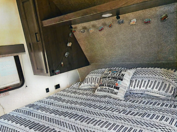 Inviting RV rental bedroom with patterned bedding, text pillow, and charming camper decor. Ready for adventure & relaxation.. Highland Ridge RV Open Range 2021