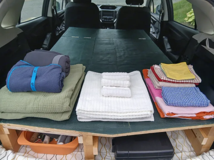 Organized car camping bed setup with neatly stacked linens & under-platform storage, a great RV rental alternative.. Subaru Impreza 2018