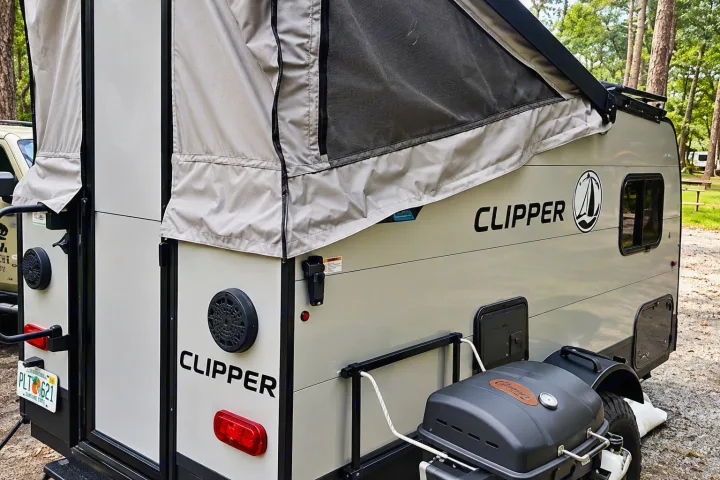 Detailed view of a beige Clipper pop-up RV rental, featuring a mounted grill. Great for camping trips and outdoor travel.. Coachmen Clipper 2022