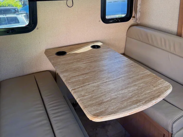 Comfortable RV rental dinette featuring a spacious table with cup holders and cozy bench seating for enjoyable travel.. Thor Windsport 2018