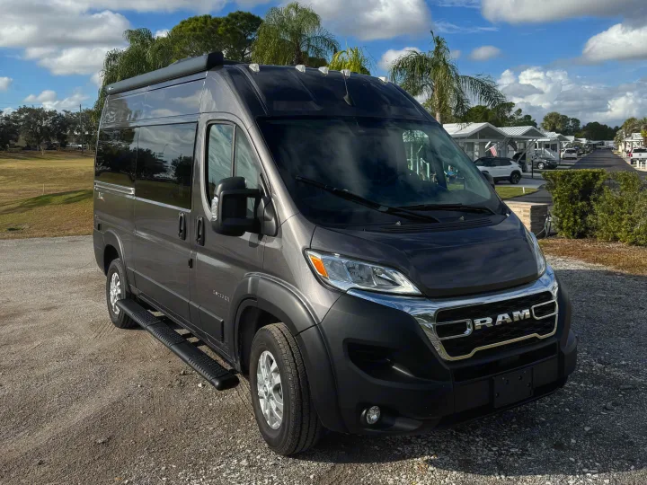 This dark grey Ram ProMaster camper van, ideal for RV rental, is parked outdoors on a sunny day.. Entegra Coach ARC 2025