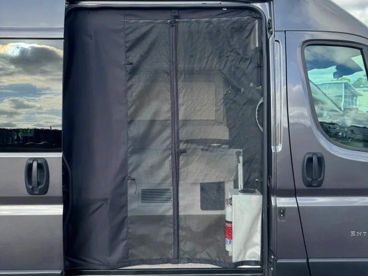 RV rental with a black mesh screen on the sliding door, showing the interior and a fire extinguisher, perfect for bug-free camping.. Entegra Coach ARC 2025