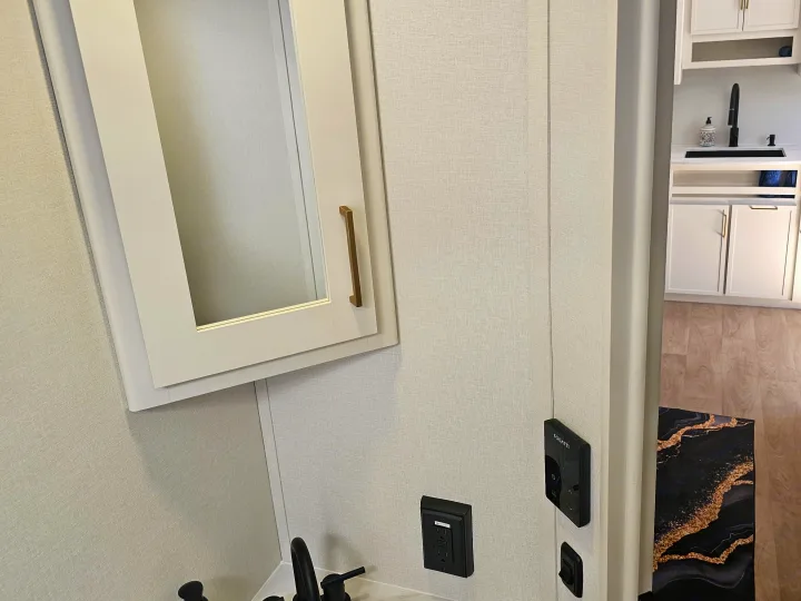 Close-up of a modern rv rental interior: white cabinets, black faucet, textured walls, and a FOGATTI control panel.. Grand Design Transcend Xplor 2026