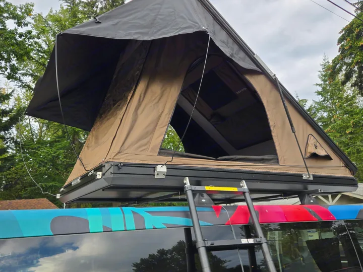 Hard-shell rooftop tent open on a brightly wrapped vehicle, ideal for your next RV rental getaway.. Ford Transit 2017