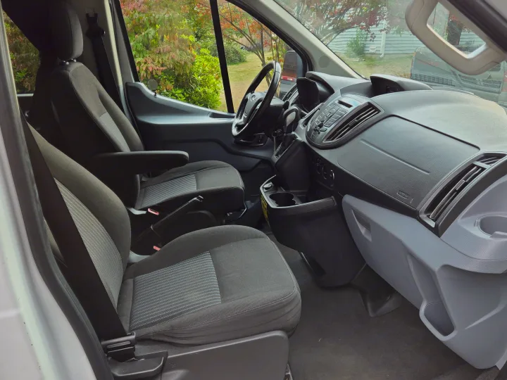 Inside an RV rental van, showing driver & passenger seats, dashboard, and outside view. Perfect for your next adventure.. Ford Transit 2017