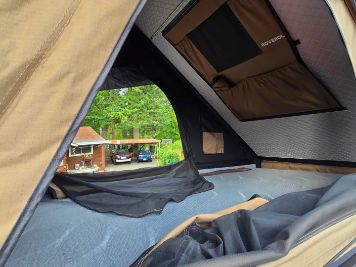 Inside a Roverol rooftop tent, perfect for an RV rental trip, offering a comfortable view of a suburban backyard.. Ford Transit 2017