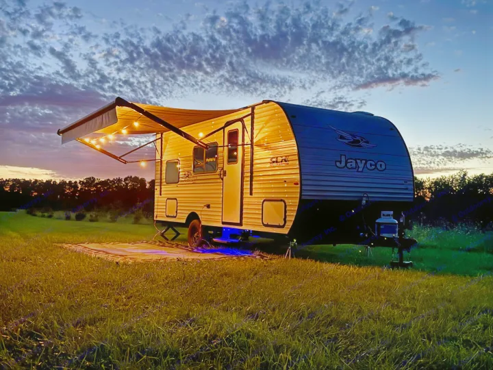 A lit Jayco rv rental glows under a stunning twilight sky, parked in a grassy field for a perfect outdoor camping experience.. Jayco Jay Flight SLX Sport Edition 2026
