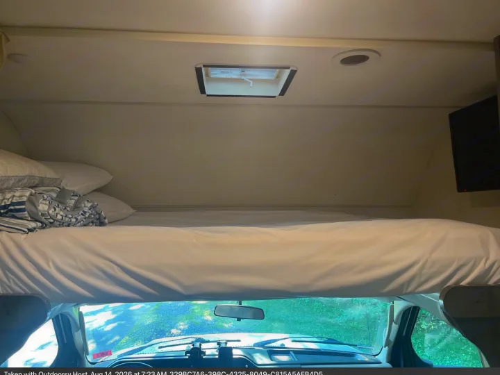 This RV rental offers a comfy overhead bed with white linens, a ceiling skylight, and a front cab view.. Winnebago Minnie Winnie 2018