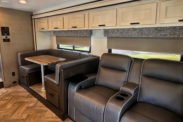 Modern RV rental interior featuring a U-shaped dinette, two recliners, and overhead storage cabinets.. Forester Classic 2021