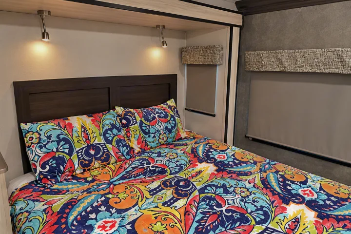 Bright and cozy RV rental bedroom interior, featuring vibrant paisley bedding, reading lights, and roller shades.. Forester Classic 2021