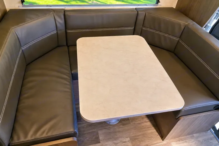 Inside an RV rental: a comfortable U-shaped dinette with a light table and dark cushions for dining and relaxation.. Winnebago Minnie Winnie 2024