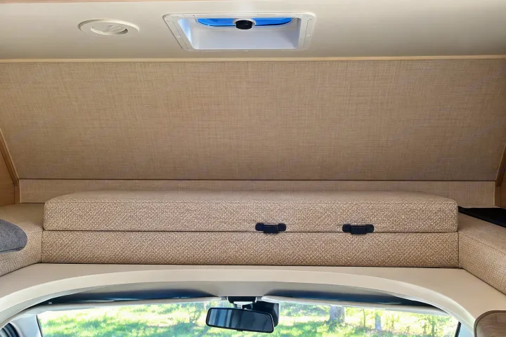 Explore the cozy cab-over bunk of this RV rental, featuring a comfortable mattress, overhead vent, and skylight.. Winnebago Minnie Winnie 2024