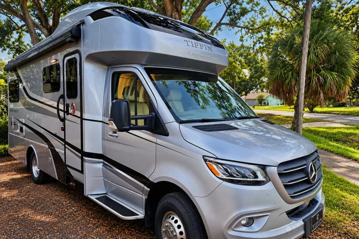 Luxury Tiffin Wayfarer Class C RV rental, silver with black accents, parked outdoors under green trees. Your adventure awaits!. Tiffin Wayfarer 2020