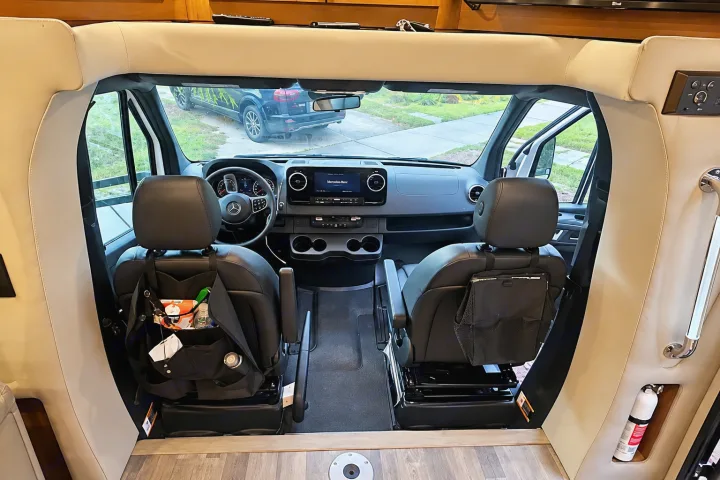 RV rental's Mercedes-Benz Sprinter cabin: modern dashboard, front seats with organizers, and road ahead view.. Tiffin Wayfarer 2020