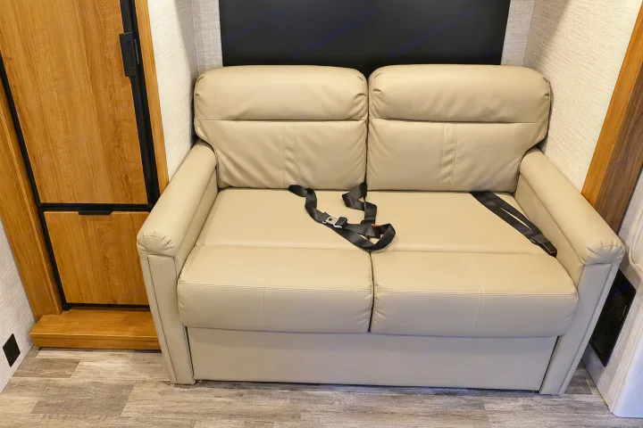 RV rental: Beige sofa with seatbelts in a camper interior, alongside a wood cabinet, offering safe travel seating.. Tiffin Wayfarer 2020