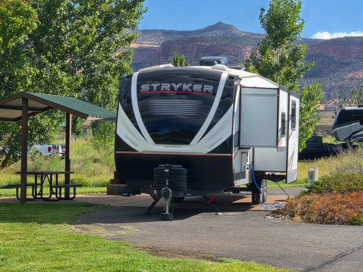 An rv rental (Stryker toy hauler) with its slide-out extended, parked at a scenic campsite with mountains and trees.. Cruiser Rv Corp Stryker 2025