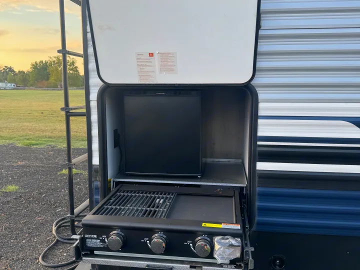 RV rental outdoor kitchen equipped with an Ever Chill mini-fridge and Greystone grill/griddle for convenient camping meals.. Forest River Palomino Puma 2025