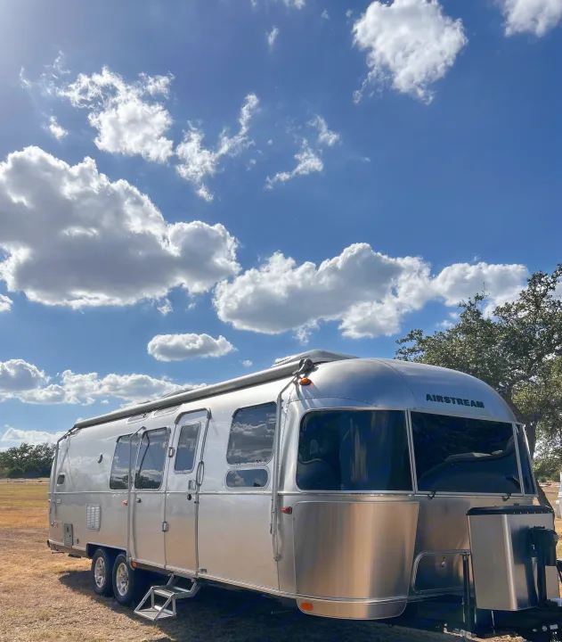 Silver Airstream travel trailer under a sunny sky with clouds, perfect for your next rv rental adventure.. Airstream Flying Cloud 2022