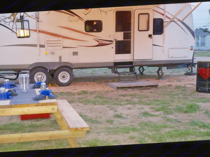 An RV rental set up at a campsite with an outdoor kitchen, picnic table with place settings, and lantern, ready for guests.. Other Other 2013