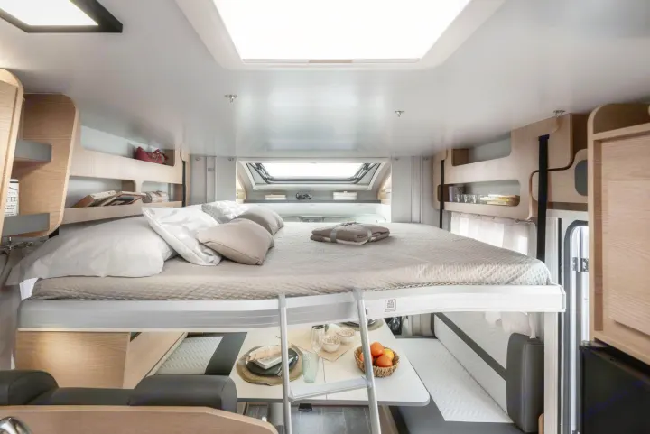 Modern RV rental interior with a cozy drop-down bed above a dining area, featuring skylights for compact living.. Giottiline Sienna 396 2027