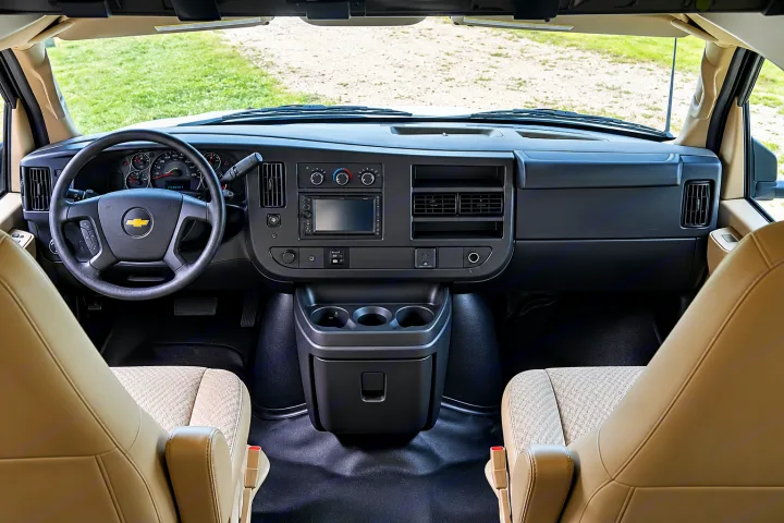 Inside an RV rental van: driver's perspective with steering wheel, dashboard, infotainment screen, and front seats.. Forest River Coachmen Freelander 2018