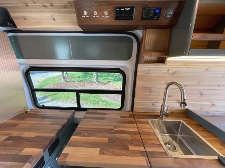 RV rental: Bright kitchen area with wood countertops, stainless sink, overhead controls, and a window showcasing outdoor scenery.. Off Grid Adventure Vans Sarge 2019
