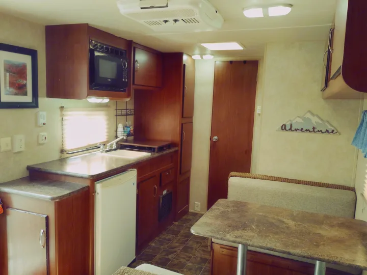 This RV rental offers a compact kitchen with a microwave, sink, and fridge, plus a cozy dinette for dining and relaxation.. Forest River Salem Cruise Lite 2014