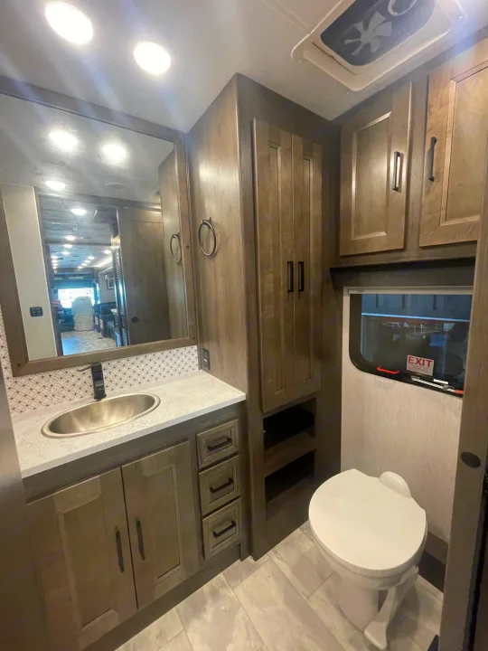 This modern RV rental bathroom features a vanity, sink, mirror, storage, toilet, and window, showcasing its compact and functional design.. Coachmen MIRADA 35ESF 2026
