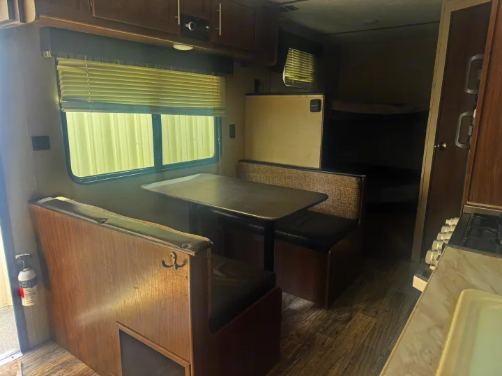 RV rental interior shows a dinette (table and benches), kitchenette with stove and sink, refrigerator, and bunk beds.. Keystone RV Hideout LHS 2019