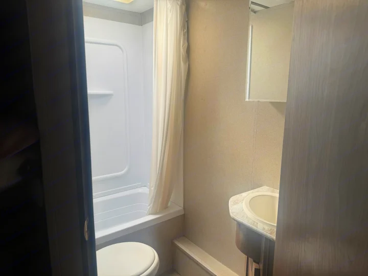This RV rental bathroom shows a shower-tub combo, toilet, and sink vanity with a medicine cabinet, all in a compact space.. Keystone RV Hideout LHS 2019