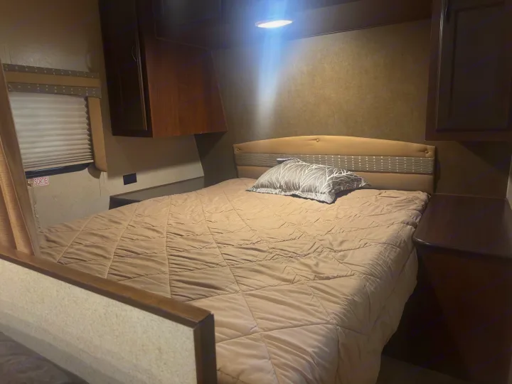 Cozy rv rental bedroom interior with a bed, storage cabinets, and a window. Ideal for comfortable camper adventures.. Jayco Jay Flight 2015