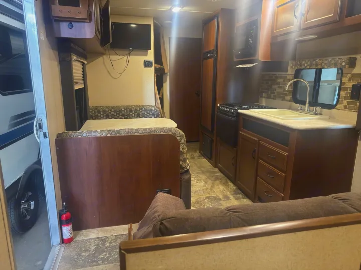 Explore this clean RV rental's cozy interior, featuring a kitchen, dinette, sofa, and TV for comfortable travel.. Jayco Jay Flight 2015