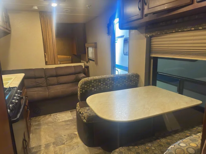 Spacious RV rental interior: kitchen on left, brown sofa, and patterned dinette with table. Bright living space for your trip.. Jayco Jay Flight 2015