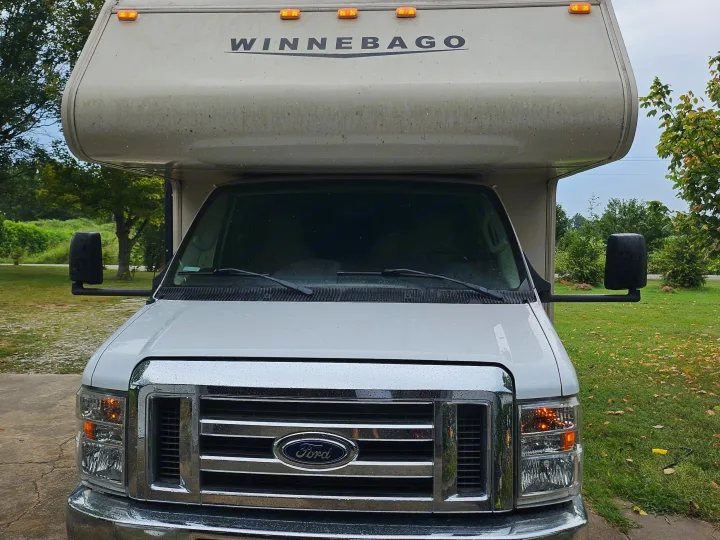 Front view of a white Winnebago Class C RV rental with Ford chassis, parked outside after rain.. Winnebago Minnie Winnie 2018