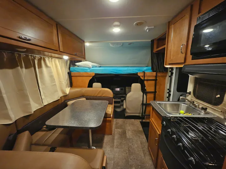 rv rental interior featuring a kitchenette, dining booth, and cabover bed. Ideal for comfortable road trips.. Winnebago Minnie Winnie 2018
