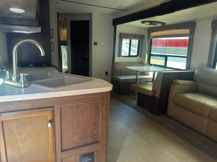 Inside an RV rental: a bright kitchen with sink, dinette booth, and cozy sofa for a comfortable journey.. Starcraft GPS 2018