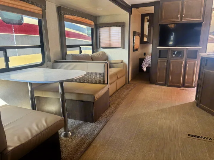 Spacious RV rental interior featuring a dining booth, sofa, entertainment center, and modern decor for comfortable travel.. Starcraft GPS 2018