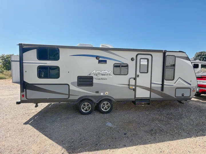 Gray Apex Ultra Lite Coachmen travel trailer, perfect for your next RV rental adventure, parked on gravel under clear sky.. Coachmen Apex 2020