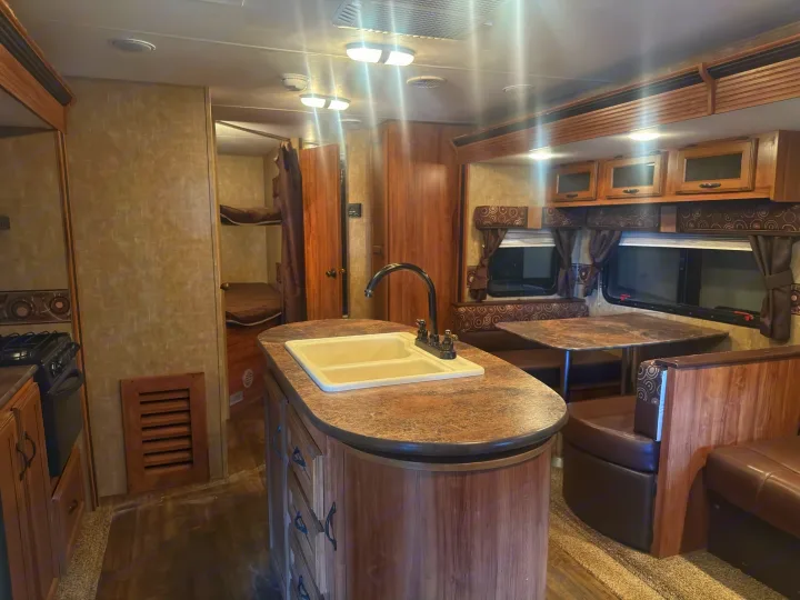 Step inside this RV rental featuring a kitchen island with a double sink, dining booth, and bunk beds for family comfort.. KZ C291IKS 2015