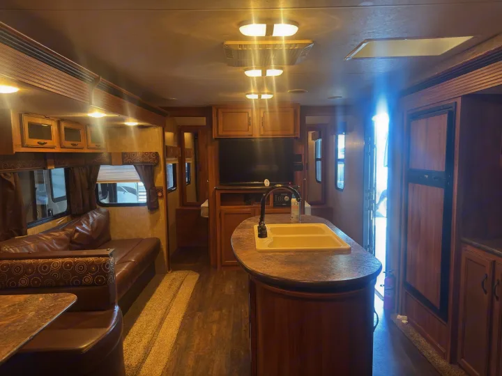 This rv rental features a cozy interior with a kitchen island, dining booth, living area, and bright overhead lighting.. KZ C291IKS 2015