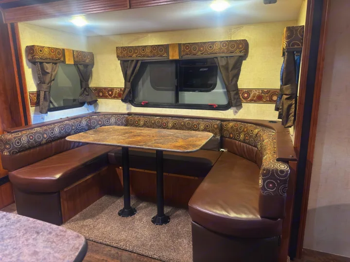 U-shaped RV dinette area, perfect for an rv rental, featuring comfortable brown booth seating & a table.. KZ C250BHS 2015