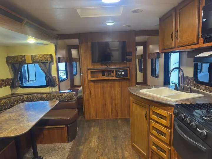 Well-equipped rv rental interior featuring a kitchen, dining booth with patterned cushions, and entertainment system.. KZ C250BHS 2015
