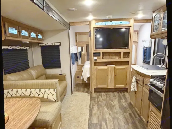 RV rental interior: A comfortable living area with couch, dining booth, TV entertainment center, and a compact, functional kitchen.. Coachmen Coachmen Freedom Express Ultra Lite 292BHDS 2019