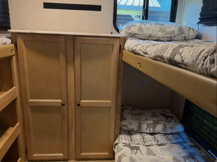 RV rental interior: cozy bunk beds with moose-themed bedding & light wood storage cabinets. Ideal for family trips.. Coachmen Coachmen Freedom Express Ultra Lite 292BHDS 2019