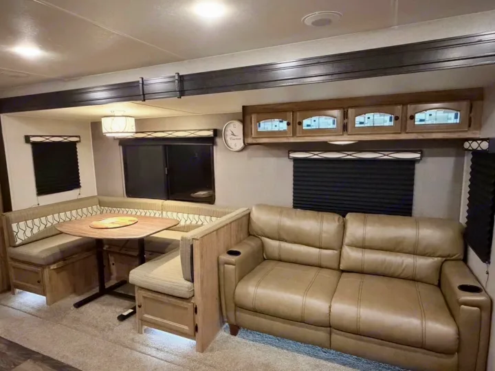 This rv rental interior features a bright living area with a U-shaped dinette, table, and comfy leather sofa.. Coachmen Coachmen Freedom Express Ultra Lite 292BHDS 2019