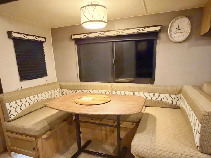 Cozy RV rental dinette with U-shaped seating, wooden table, and blinds, perfect for dining or relaxing.. Coachmen Coachmen Freedom Express Ultra Lite 292BHDS 2019