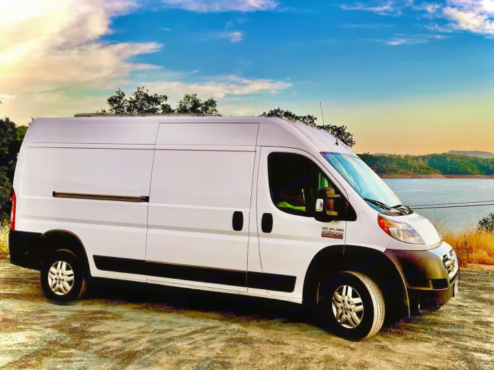 RV rental: a white Ram ProMaster camper van parked by a scenic lake under a colorful sky.. Dodge Ram ProMaster 2500 High Top 2018