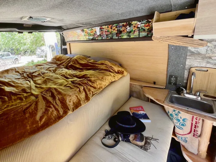 Cozy RV rental camper van interior with a comfy bed, unique decor, and a compact kitchen for comfortable travel.. Dodge Ram ProMaster 2500 High Top 2018